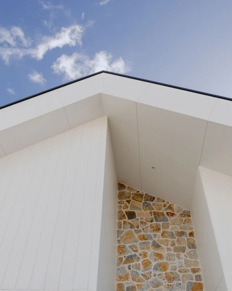 Modern coastal home exterior featuring clean white cladding and natural stone accent wall, designed and built by Indianic Homes in South West Western Australia