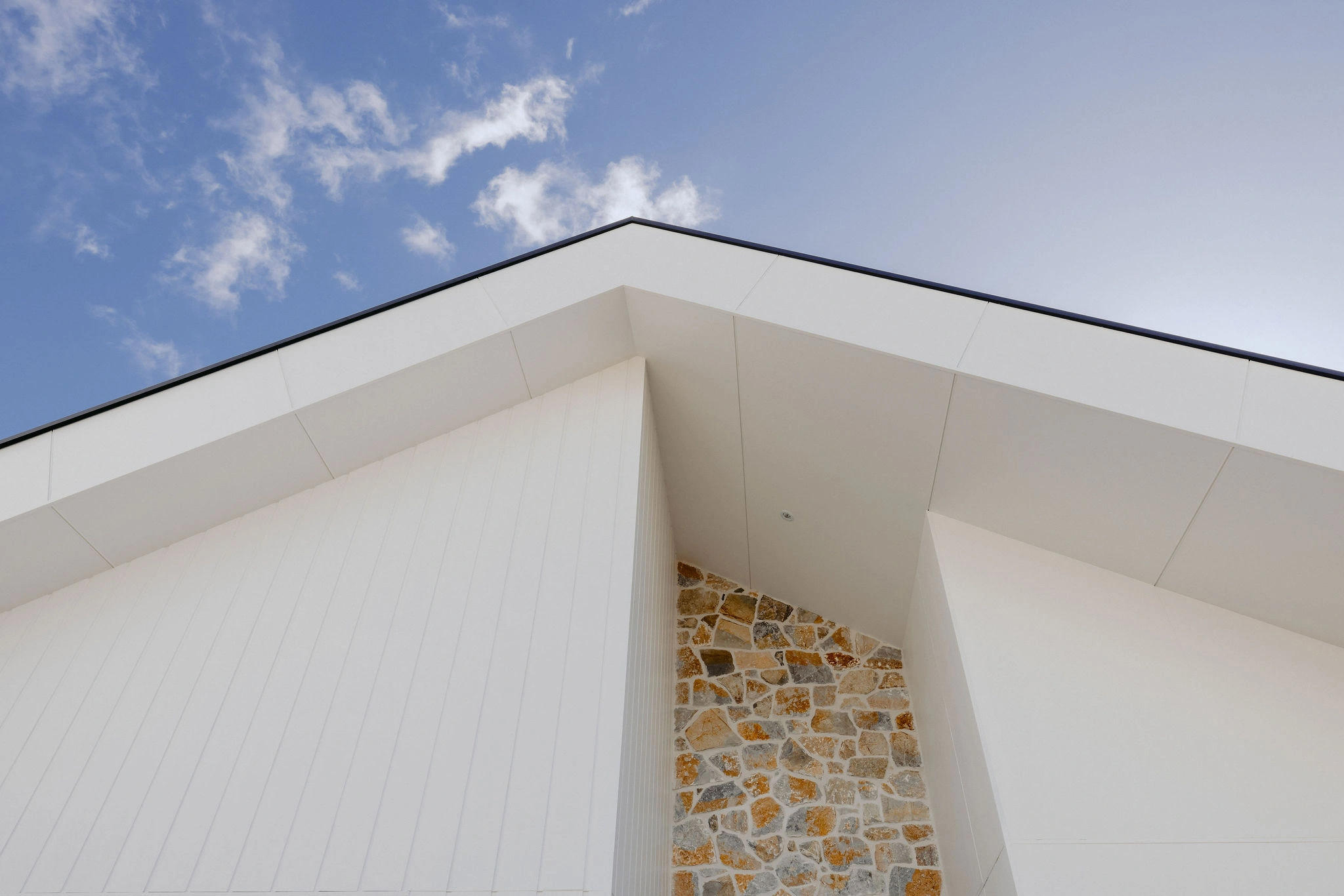 Custom coastal home by Indianic Homes - South West WA Modern coastal home exterior featuring clean white cladding and natural stone accent wall, designed and built by Indianic Homes in South West Western Australia